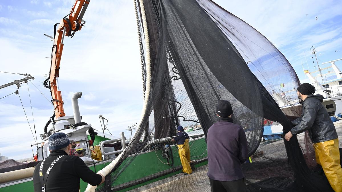 Pescadores preparan las redes y cuerdas de un barco en Castelló.