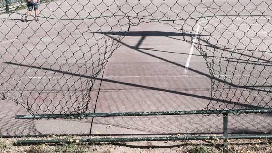 La valla perimetral de la pista de baloncesto está rota. // G.N.