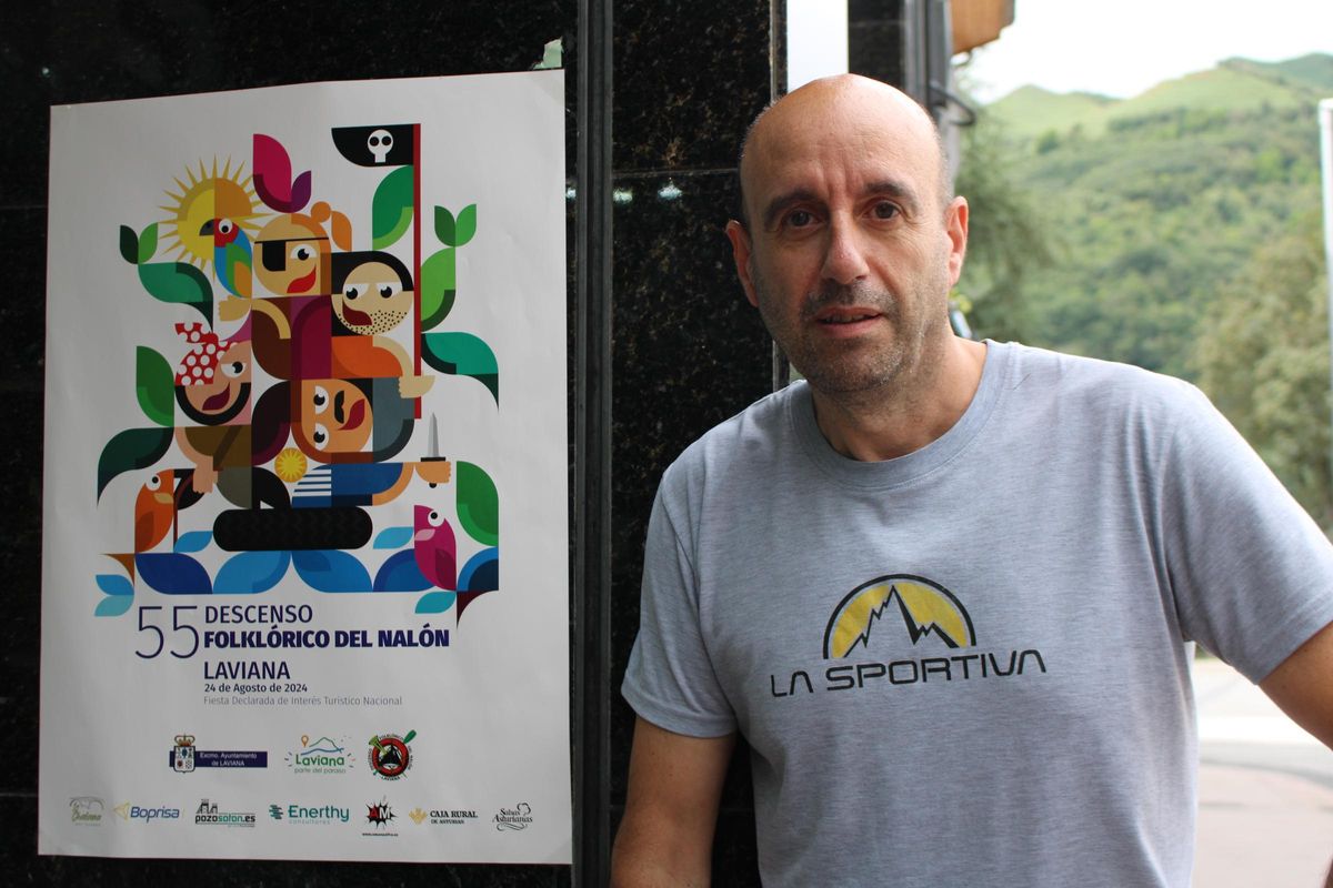El presidente de Llavianeses po'l Descensu, junto al cartel de la fiesta de este 2024 en un establecimiento de Pola de Laviana.