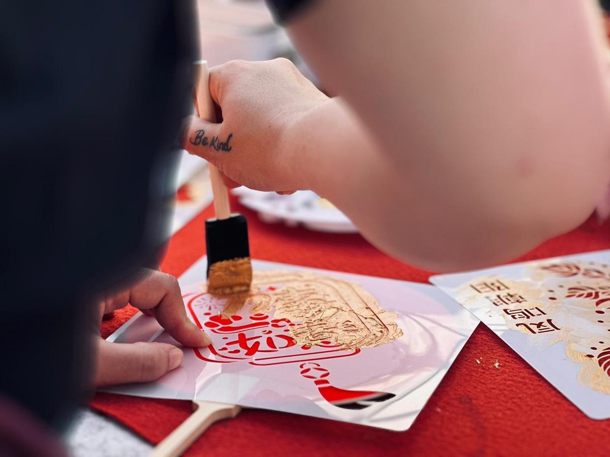 Una persona hace su propio paipay chino en uno de los talleres de la feria del Año Nuevo Chino en Sevilla.