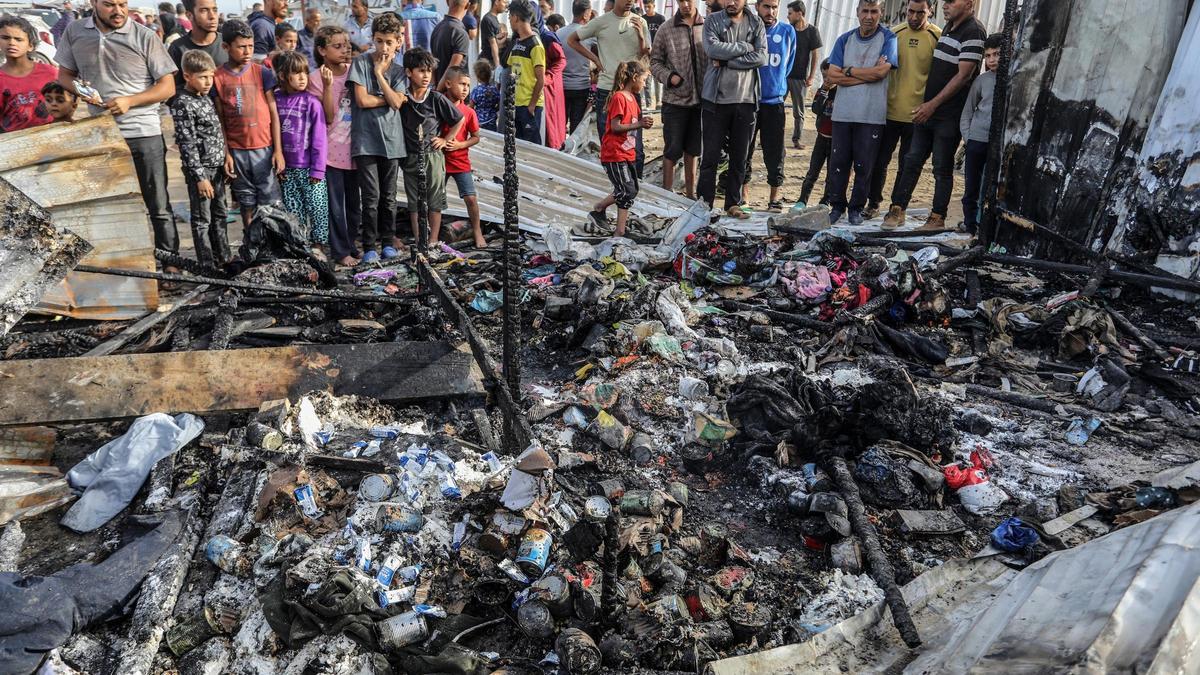 Archivo - Palestinos inspeccionan tiendas de campaña destruidas por un bombardeo del Ejército de Israel contra la "zona humanitaria" de Al Mauasi, en la Franja de Gaza (archivo)