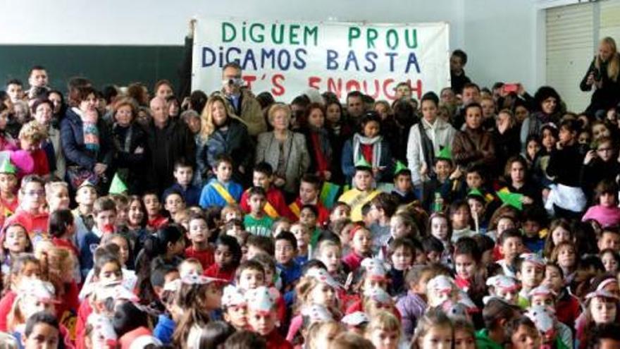 Padres y escolares del Mestre Gaspar López ondearon una pancarta contra los recortes, antes de iniciarse el festival de Navidad.