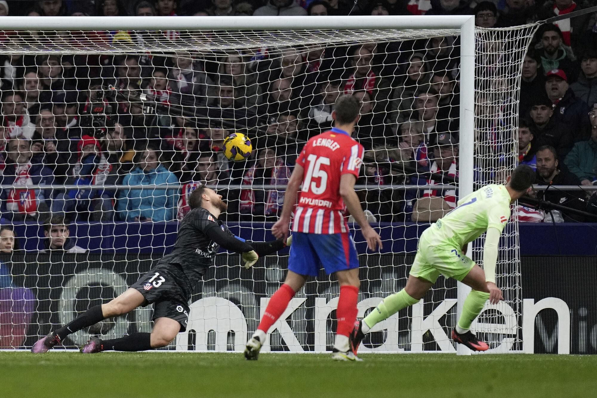 Atletico Madrid's goalkeeper Jan Oblak, left, dives but fails to save the goal from Barcelona's Ferran Torres, left, during a La Liga soccer match between Atletico Madrid and FC Barcelona at the Metropolitano stadium in Madrid, Sunday, March 16, 2025. (AP Photo/Bernat Armangue)