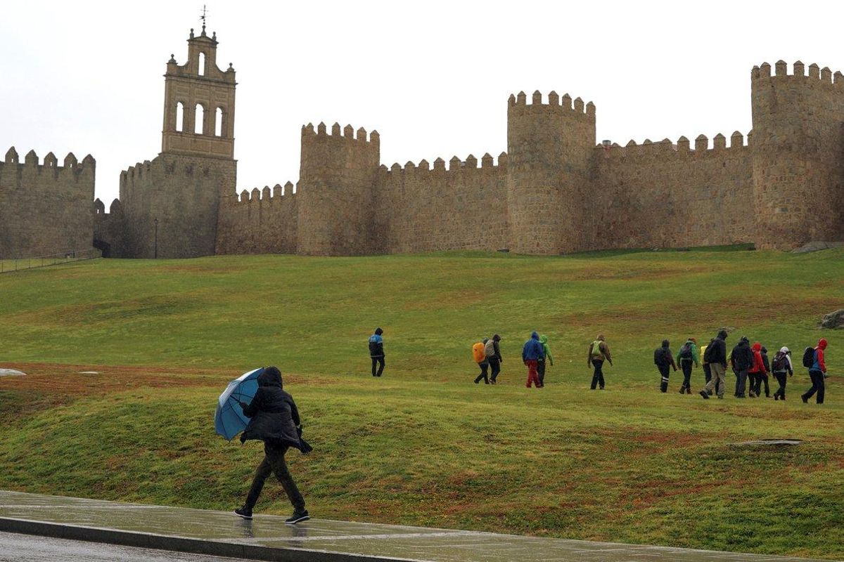 GRAF4420. ÁVILA, 20/10/2020.- Una persona se protege de la lluvia este martes junto a la muralla de Ávila en una jornada marcada por el temporal de lluvia y viento, con aviso naranja en el Sistema Central de la provincia, por el paso de la borrasca Bárbara. EFE/ Raúl Sanchidrián