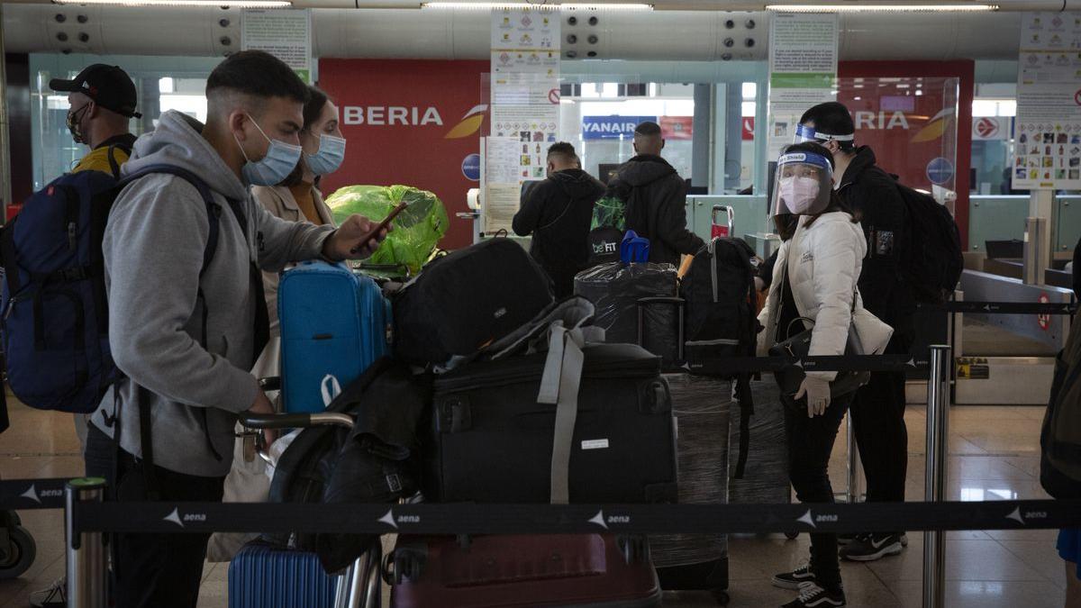 Pasajeros en el aeropuerto del Prat hacen cola para embarcar el equipaje, la pasada Navidad.