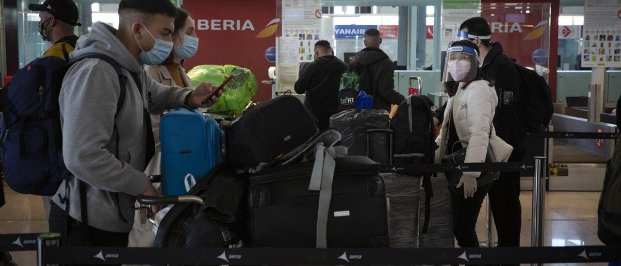Pasajeros en el aeropuerto del Prat hacen cola para embarcar el equipaje, la pasada Navidad.