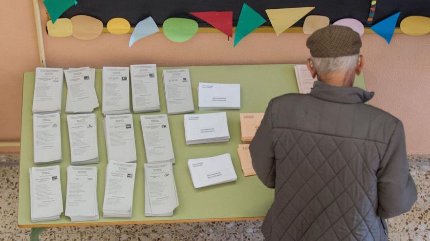 Un hombre, ante una mesa con papeletas de los distintos partidos en un colegio electoral en las elecciones de 2019. | ALEX DOMÍNGUEZ