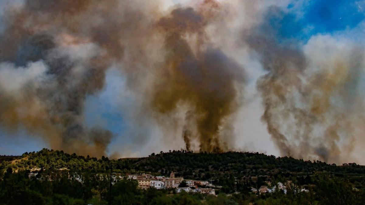 Columnas de fuego y humo tras el casco urbano de Benimassot, uno de los pueblos desalojados en el incendio de la Vall d'Ebo el pasado verano.