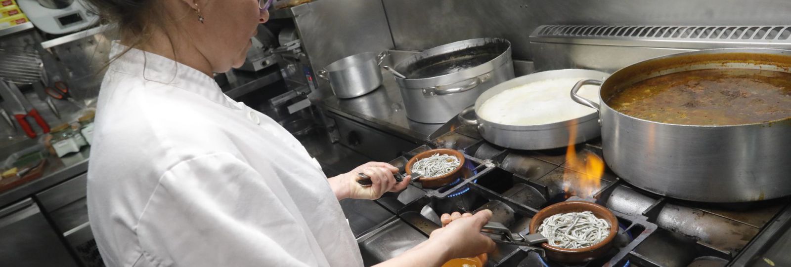 Una cocinera preparando cazuelas de angulas.