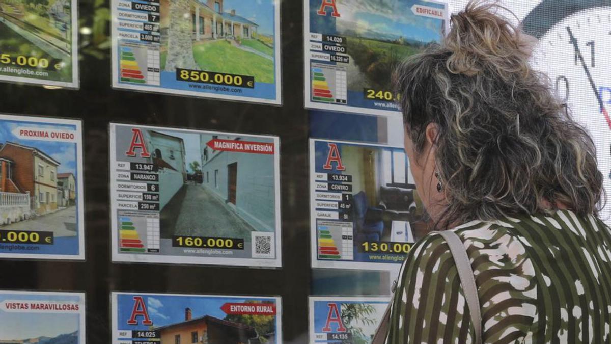 Una mujer mira el escaparate de una inmobiliaria en Oviedo. |