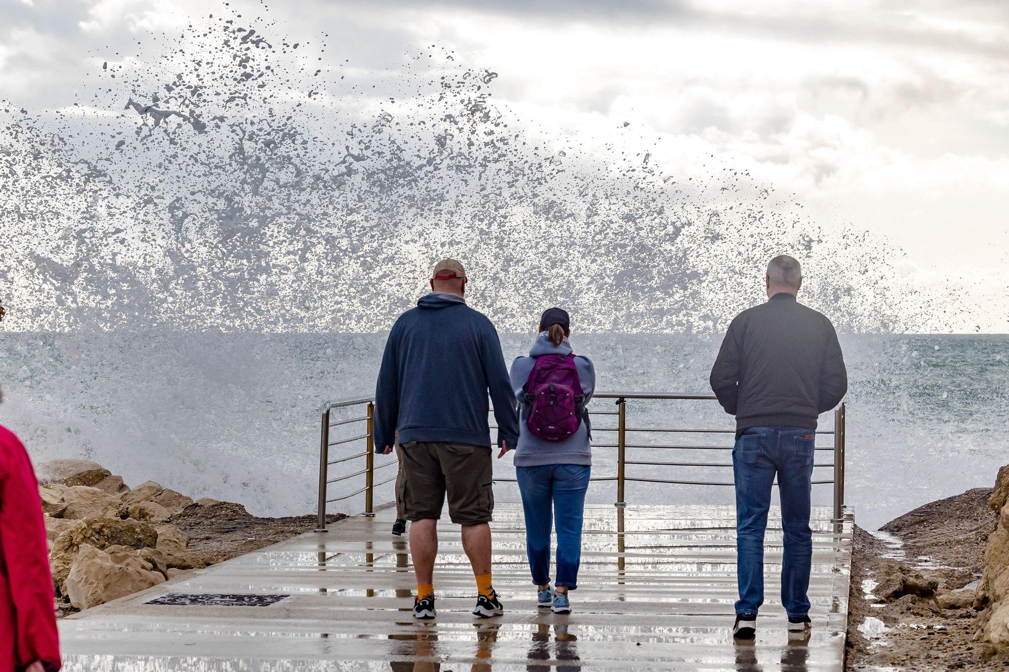 Turistas y paseantes observan el temporal de mar en la Cala de Finestrat