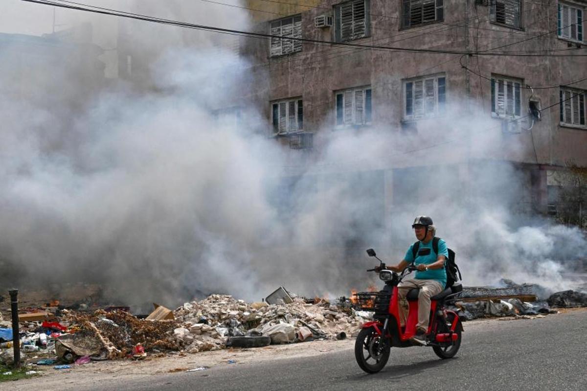Un motociclista pasa junto a un vertedero incendiado en La Habana, Cuba, el 15 de mayo de 2026.