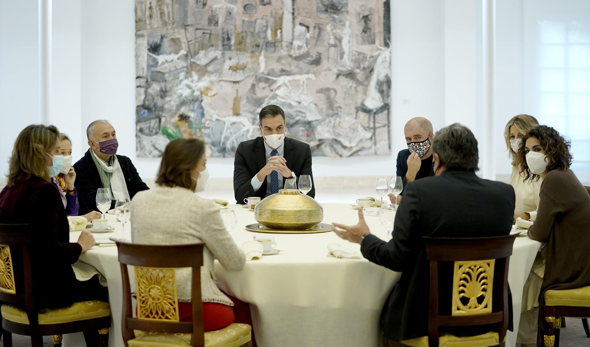 El Presidente del Gobierno, otros miembros de su Ejecutivo y los Secretarios Generales de UGT y CCOO escuchan al ministro de Inclusión durante un desayuno en el Palacio de La Moncloa
