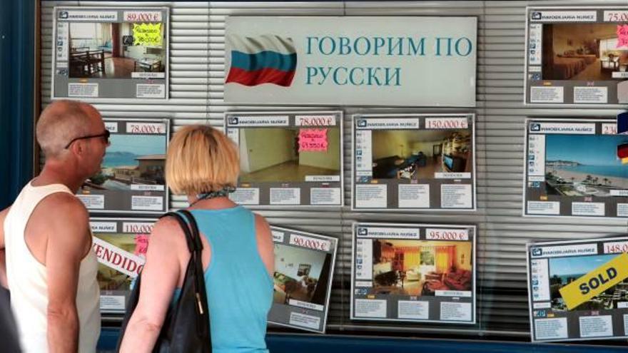 Dos turistas rusos observan una oferta de viviendas en una inmobiliaria enfocada a compradores de países del Este