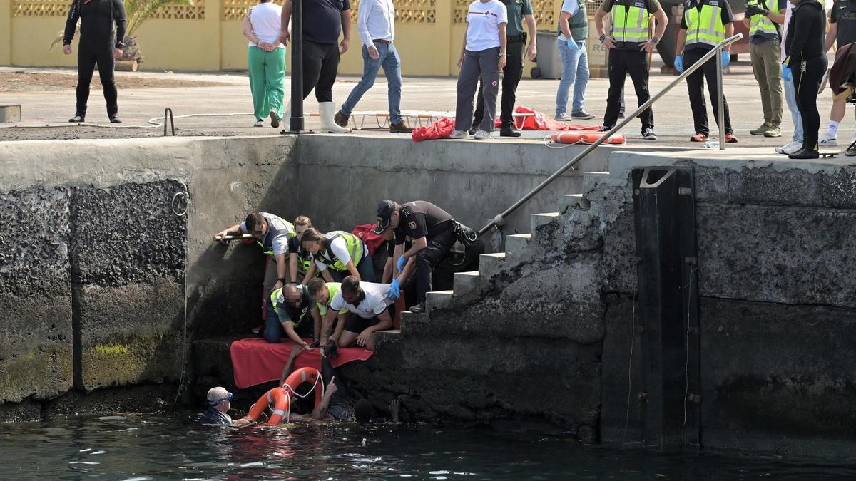 Agentes de Policía Nacional rescatan a uno de los migrantes que viajaba en un cayuco que ha volcado a su llegada al puerto de La Restinga