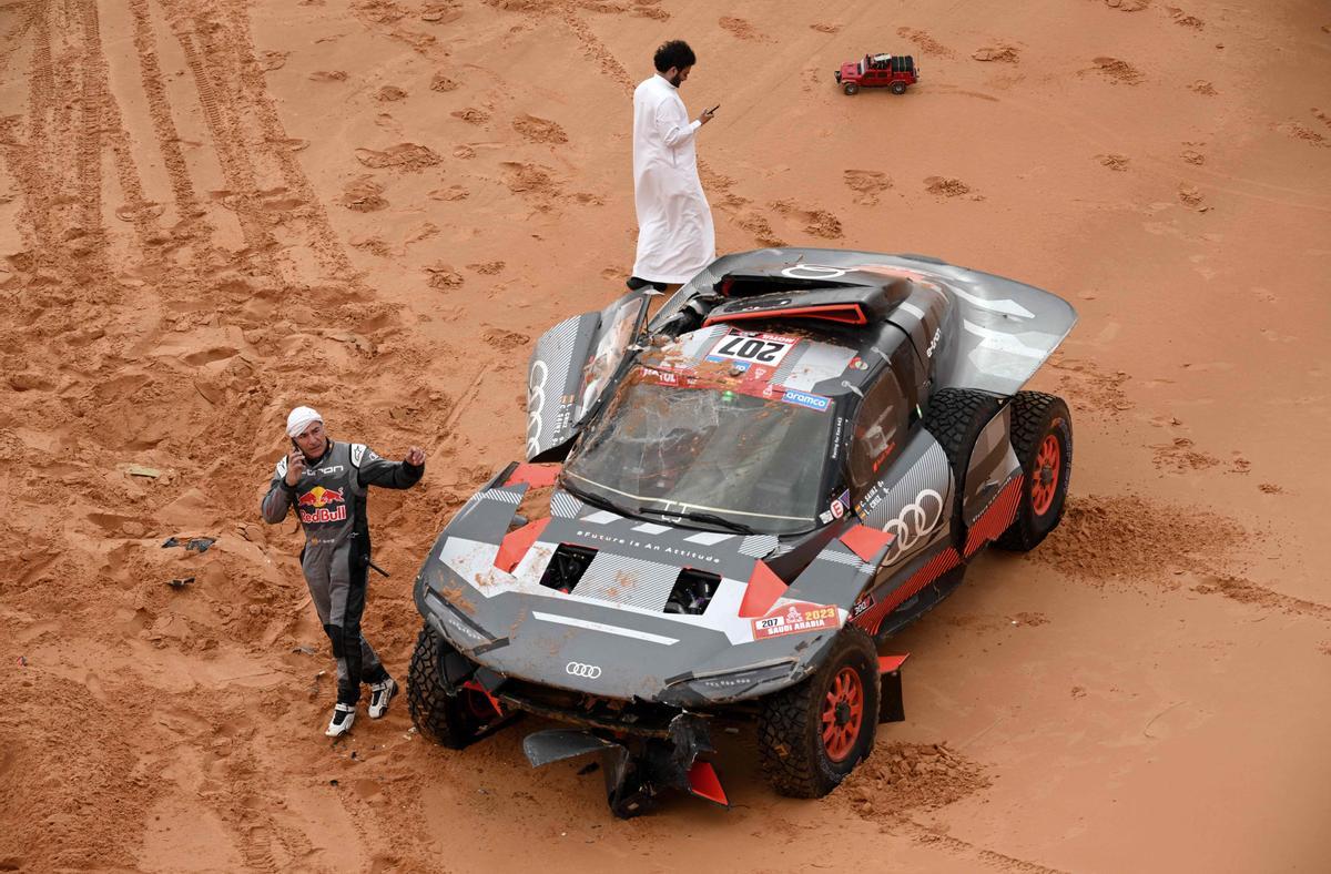 El piloto español híbrido de Audi, Carlos Sainz, camina junto a su automóvil después de un accidente.