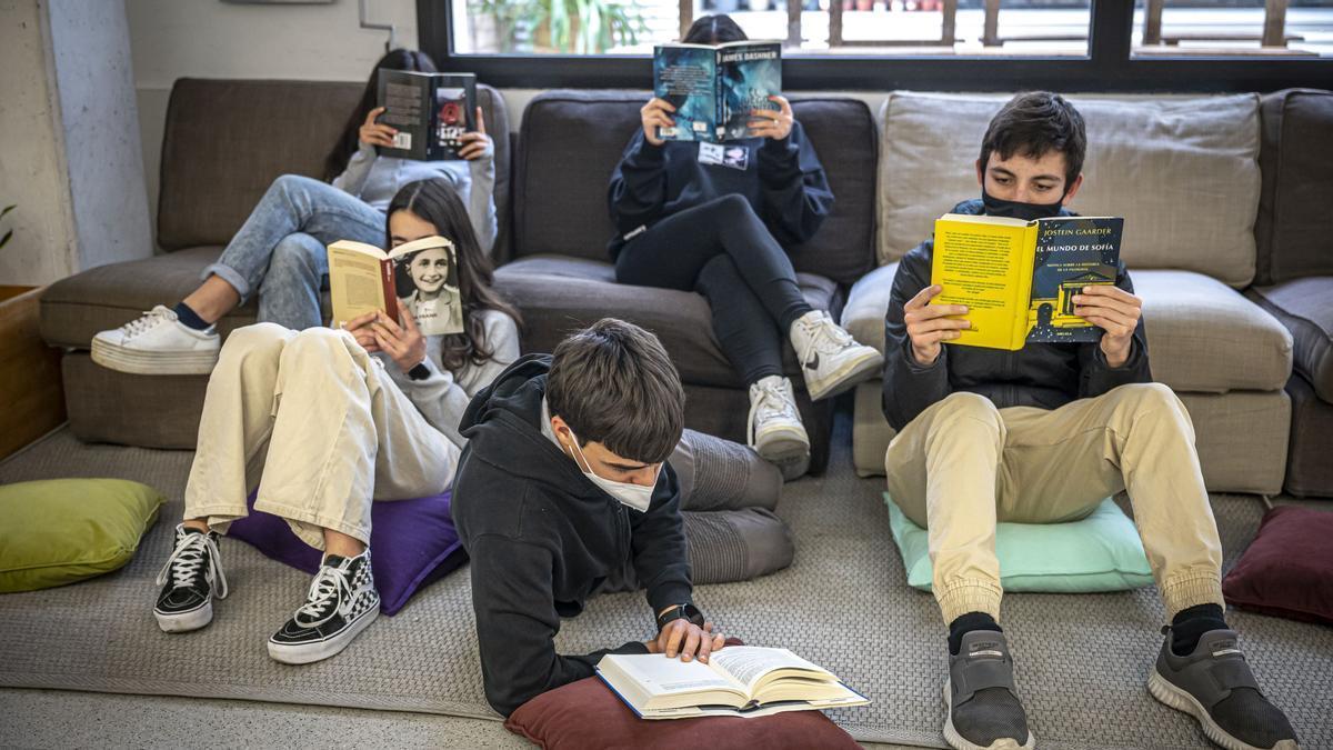Un grupo de alumnos lee durante un descanso de la jornada escolar, en Barcelona. /