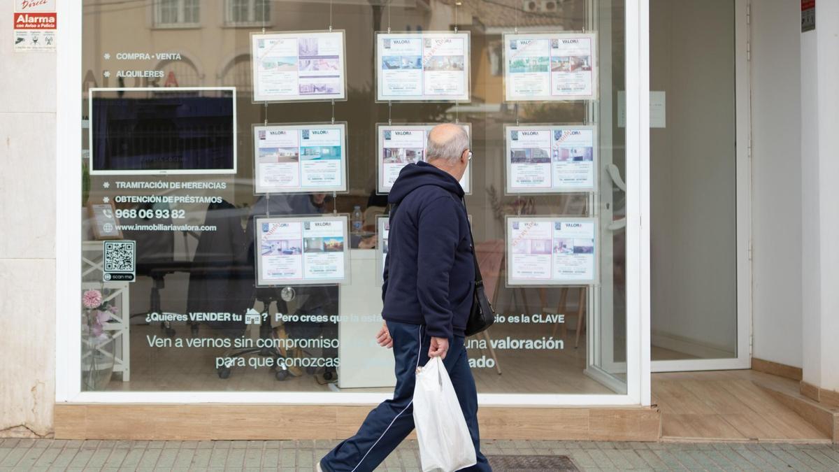 Un hombre mira los anuncios de viviendas puestos a la venta en una inmobiliaria del centro de Cartagena.