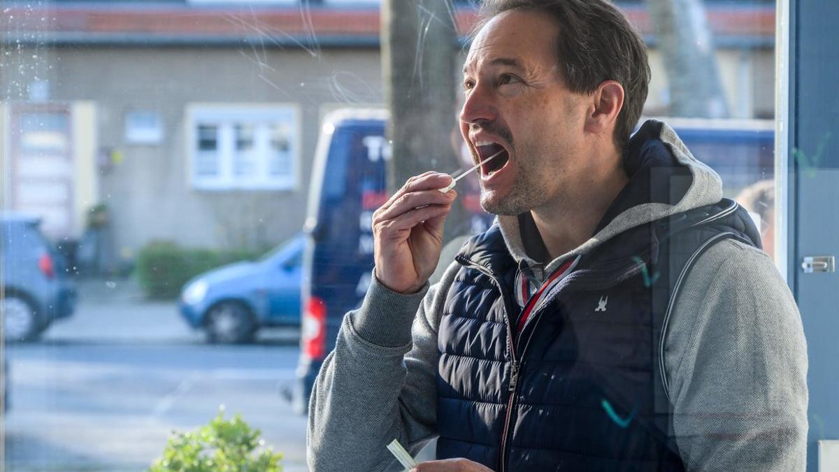 Un hombre se coge una muestra de saliva para hacerse el test de coronavirus, en un centro médico de Berlín.