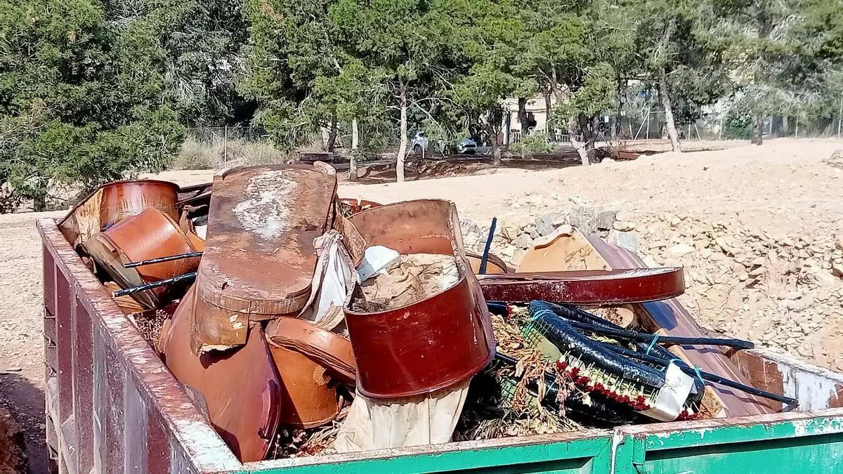 Un contenedor de obra con ataúdes, y al fondo viviendas