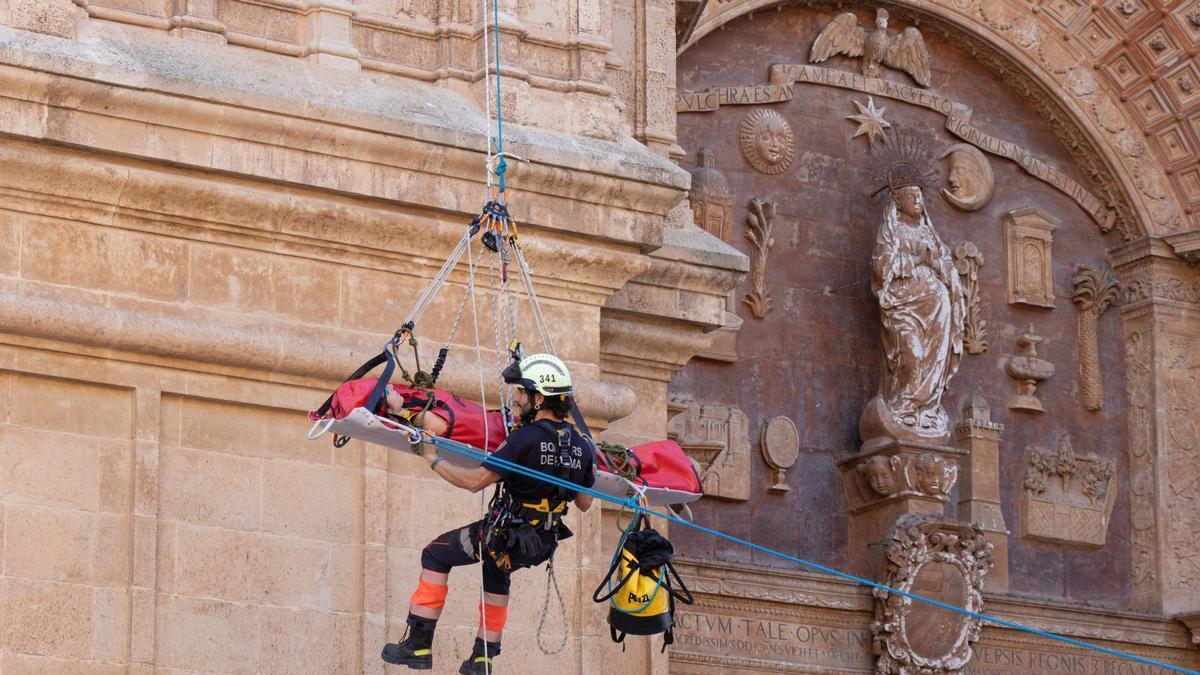 Los bomberos descienden por la fachada principal con la víctima