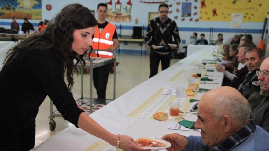 Una voluntaria entrega un plato a un hombre.