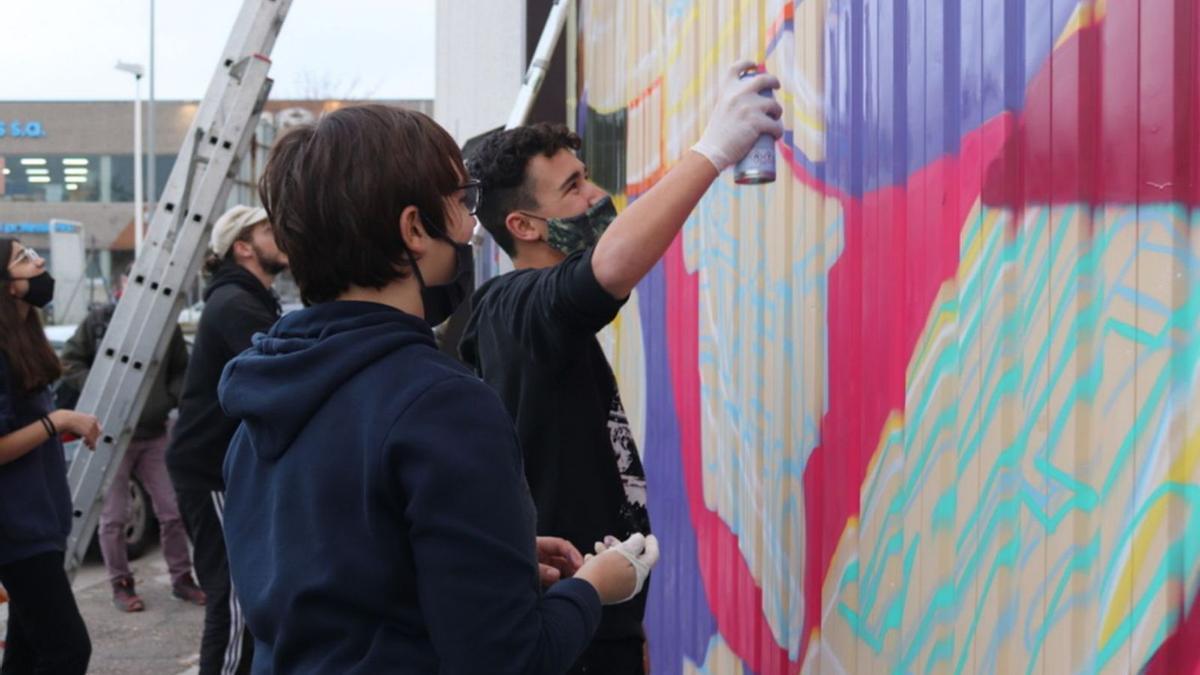 Els participants del Taller de Graffitis de Blanes, pintant la persiana de la Nau4 Espai Jove. | AJUNTAMENT DE BLANES