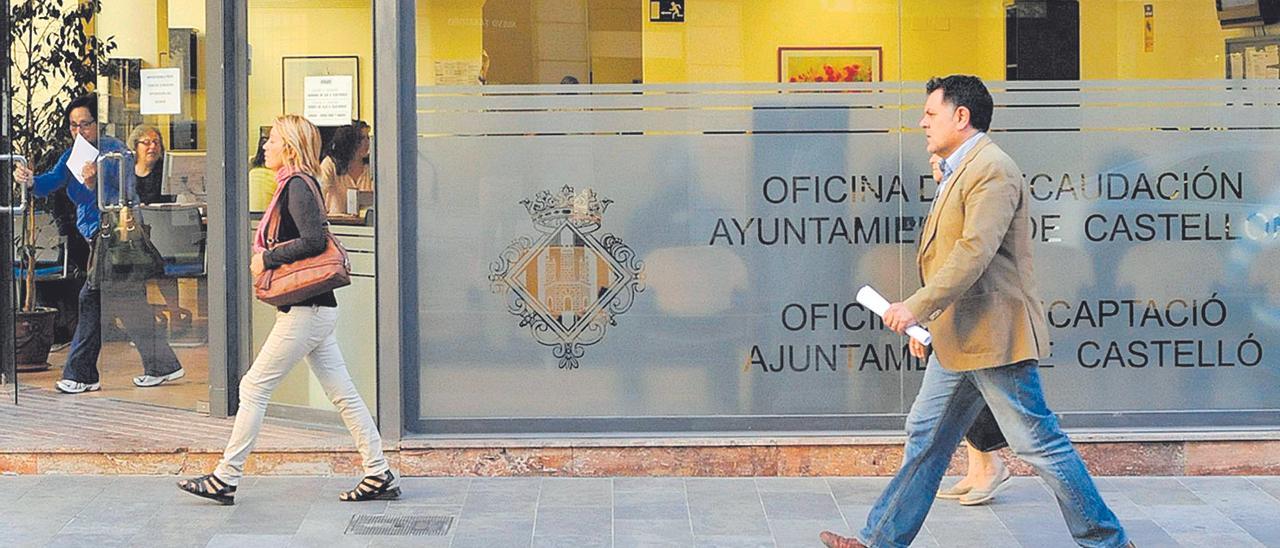 Varios viandantes pasan frente a la oficina municipal de recaudación de Castelló, en la céntrica calle Gobernado