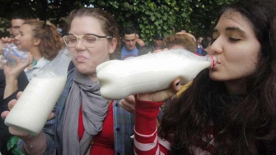 Jóvenes gallegas consumen leche repartida por ganaderos en una tractorada en Galicia.