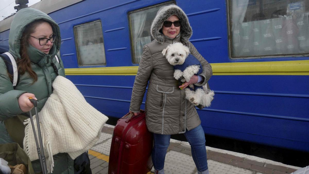 Dos mujeres con su perro que huyen de la invasión rusa de Ucrania, caminan por una plataforma antes de subir a un tren cuando salen de la ciudad de Odessa, Ucrania, el 4 de marzo de 2022.