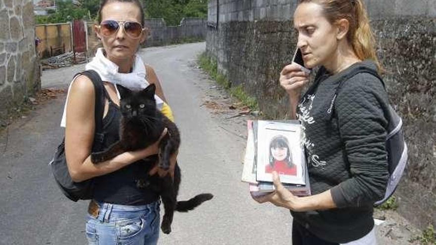 Una afectada, Sonia Alén, a la derecha, deja la zona con fotos y un libro. Una allegada la acompaña con un gato en sus brazos.