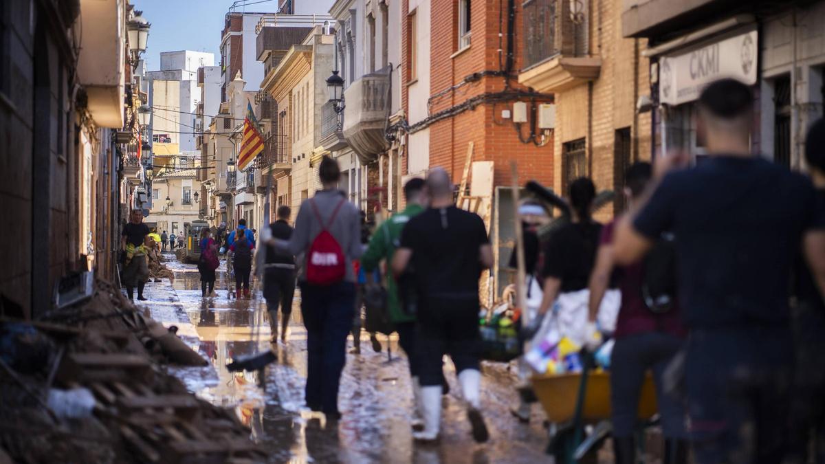 Voluntarios caminan por un calle del centro de Paiporta, el día 13 después de la dana.