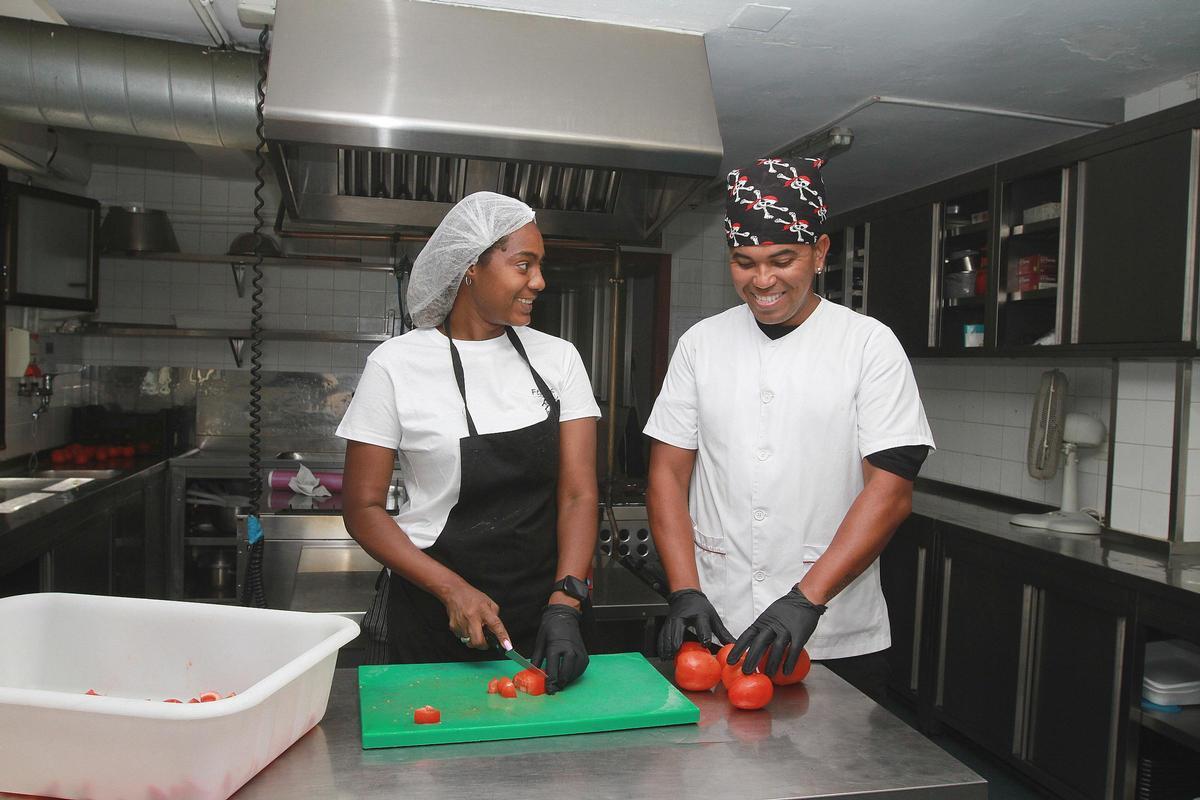 Dos de los voluntarios cortando tomates.