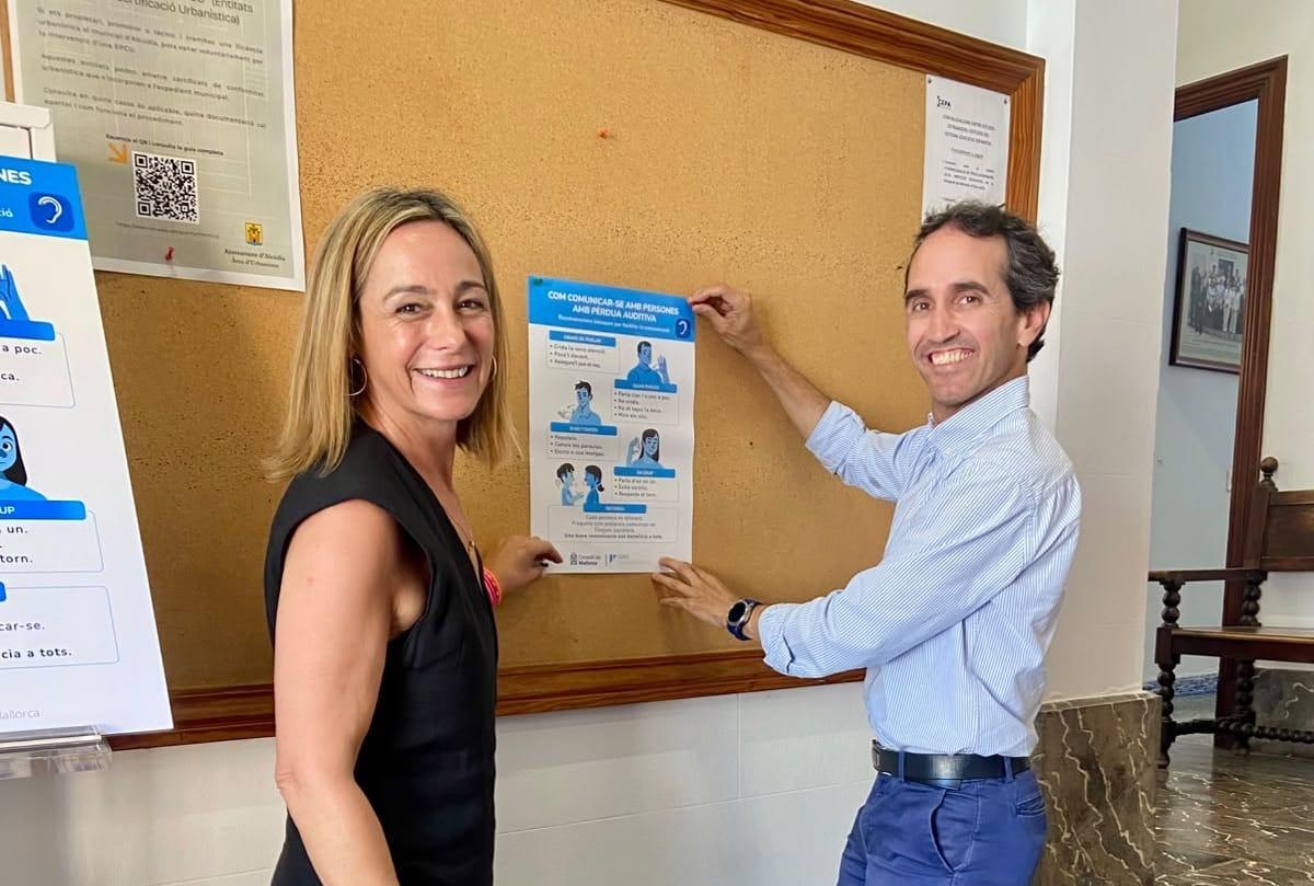 Fina Linares y Guillermo Sánchez cuelgan uno de los carteles en el vestíbulo del Consistorio.