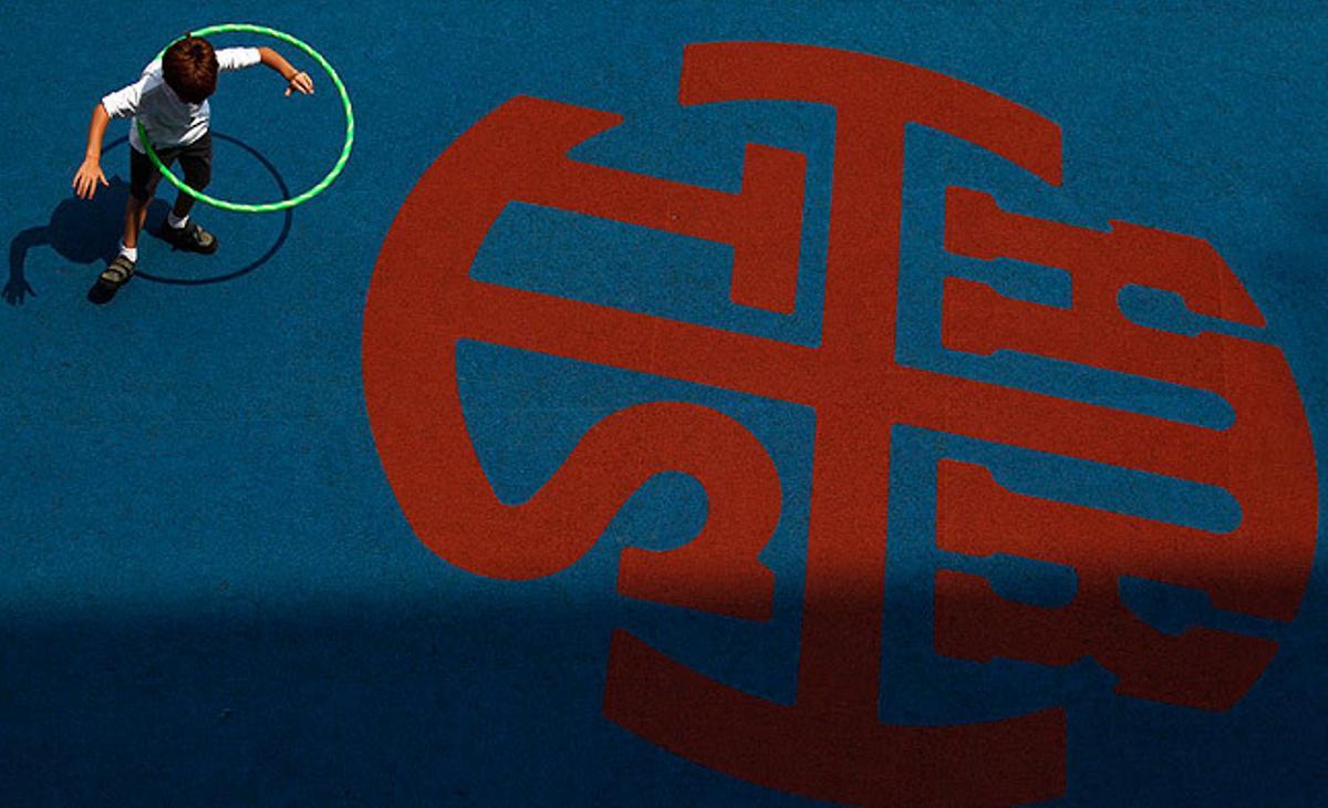 Un nen juga al pati de la seva escola, al costat de l’emblema del centre, a Hong Kong.