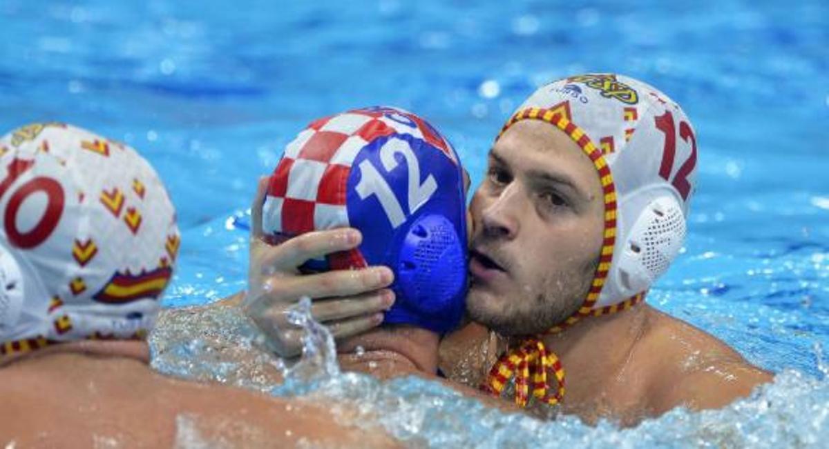 Imatge d'un partit de waterpolo el 2020 en què s'abraça un jugador espanyol (gorra blanca) amb un croat (blau amb els icònics quadrets vermells i blancs)