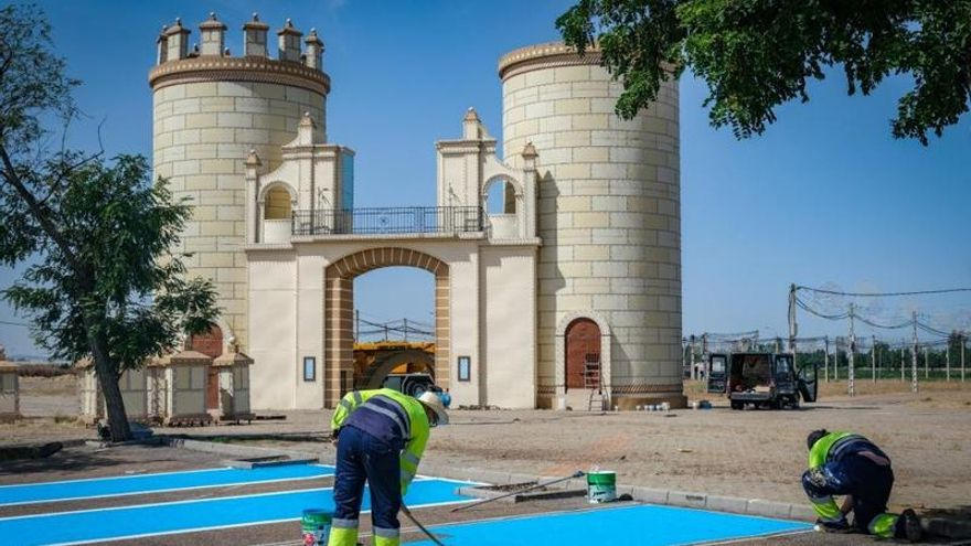 Dos operarios realizan trabajos relativos a las fiestas frente a la portada del recinto ferial.