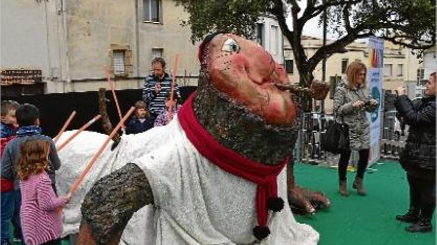 Un grup de nens i nenes picant el tió de la plaça de la Coma de Cassà de la Selva, ahir.