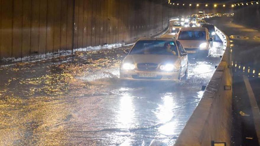 Los vehículos pasan por la bolsa de agua creada en el interior del túnel Julio Luengo, que tuvo que ser cerrado durante una hora al tráfico