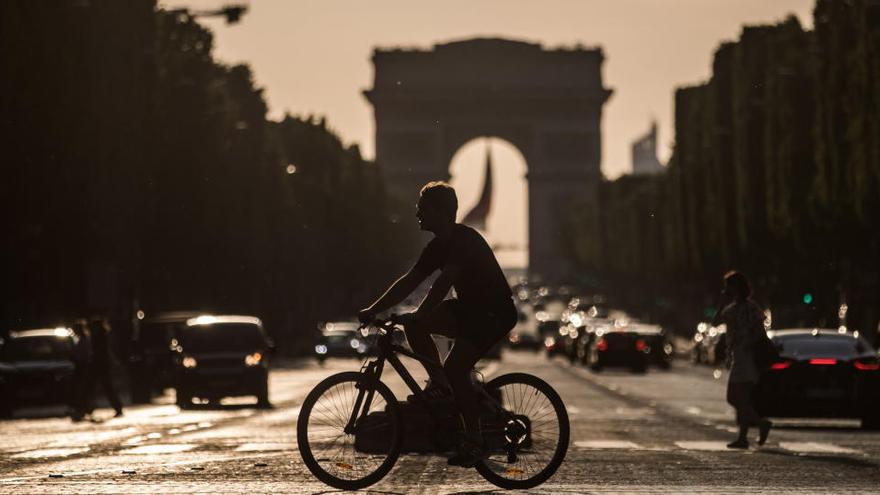 Un ciclista cruza la avenida de los Campos Elíseos, en París.