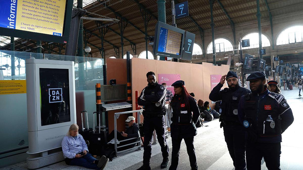 Empleados de SNCF pasan junto a una pantalla informativa en la que se indica que el tráfico ferroviario ha sido interrumpido en la Gare du Nord de París