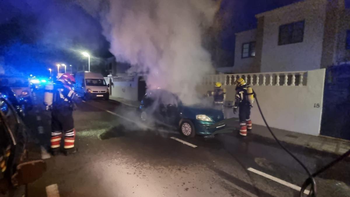 Los bomberos apagan el fuego, en la madrugada de este sábado, en un coche en la calle Chinchorro de Playa Honda (San Bartolomé).