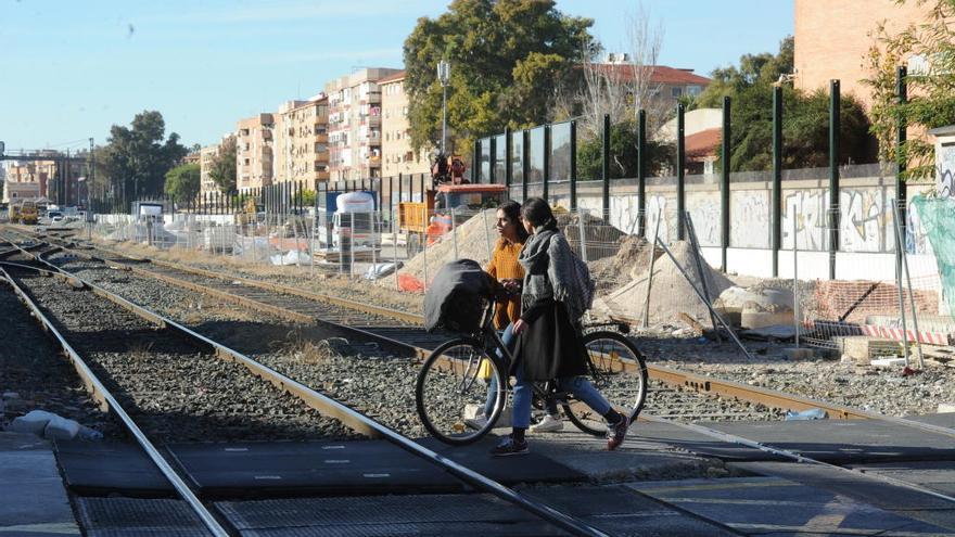 Dos jóvenes cruzan el paso a nivel de Santiago el Mayor, uno de los pocos barrios que ha crecido.