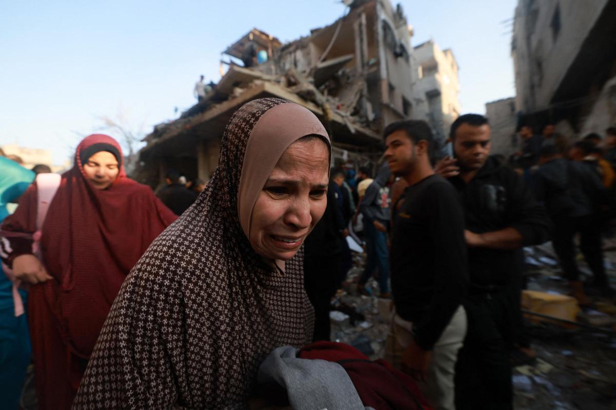 Una mujer palestina reacciona mientras la gente revisa los escombros de un edificio destruido en un ataque aéreo israelí contra el campo de refugiados de Rafah en el sur de la Franja de Gaza el 1 de diciembre de 2023, tras la expiración de una tregua de siete días entre Israel y militantes de Hamás.