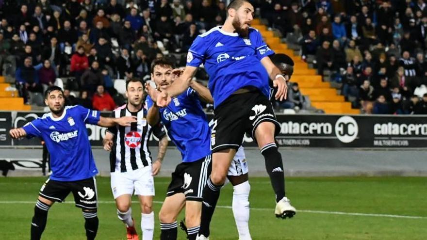 Carlos Andújar trata de despejar un balón en el área ante el acoso de un rival.