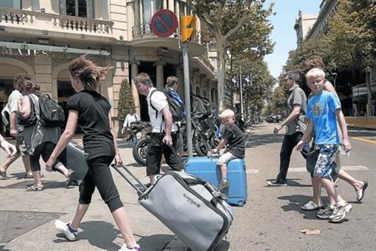 Turistes amb maletes rumb al seu allotjament, al passeig de Gràcia.