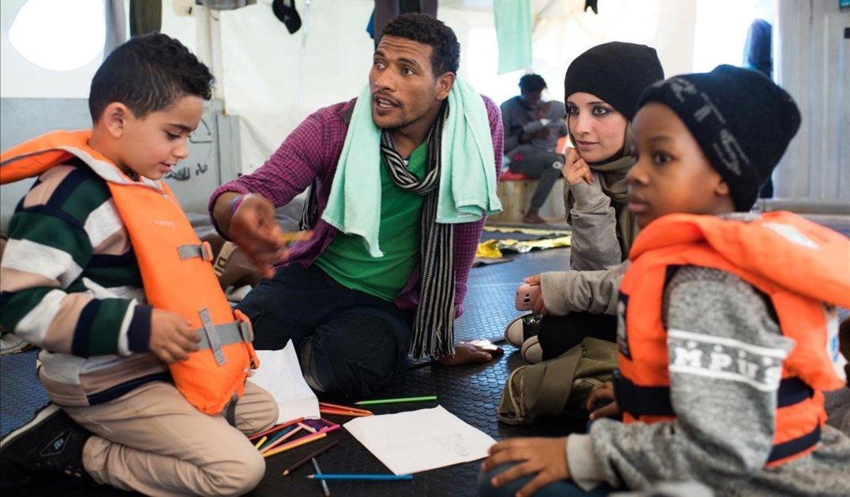Fotografia cedida por la ONG Sea-Watch que muestra a Nasreen  2d  y a su hijo Zizou  i  junto a otros inmigrantes a bordo del buque Sea Watch 3 en el mediterraneo el 23 de diciembre de 2018.