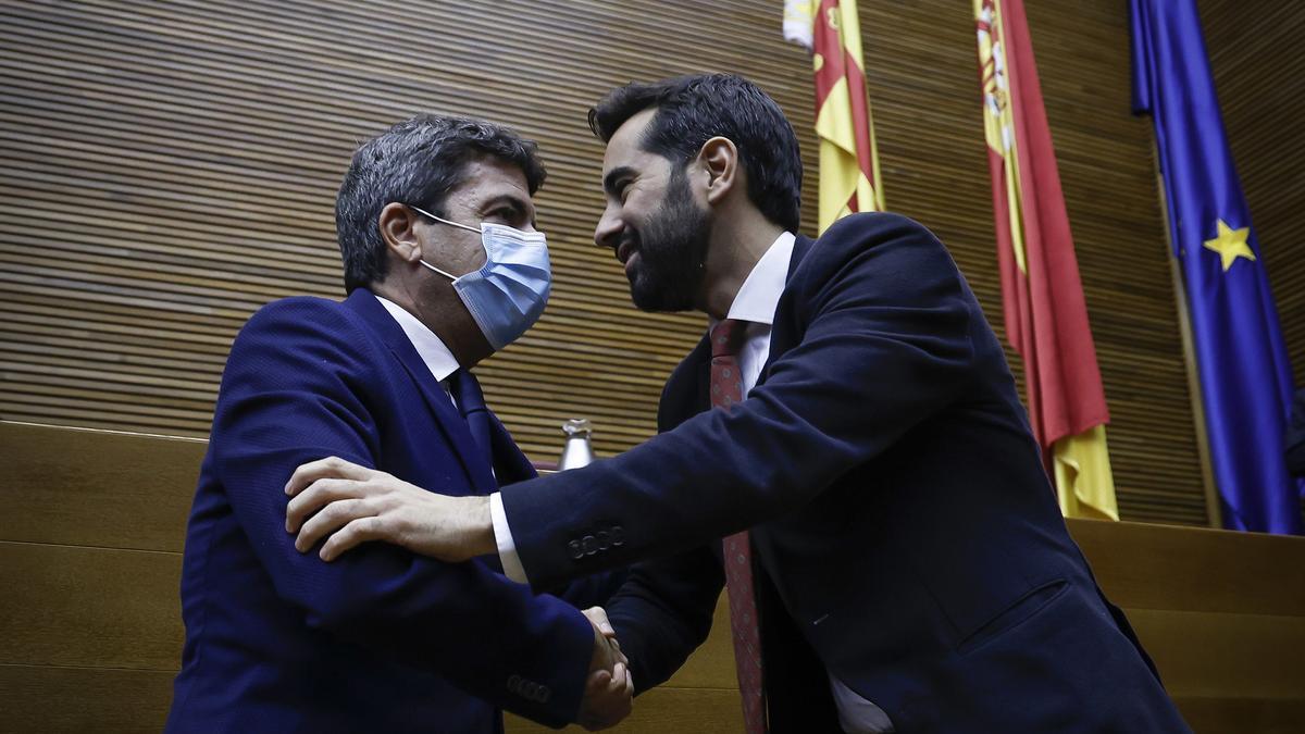 Mazón y Muñoz se saludan durante el pleno de los presupuestos, en diciembre.