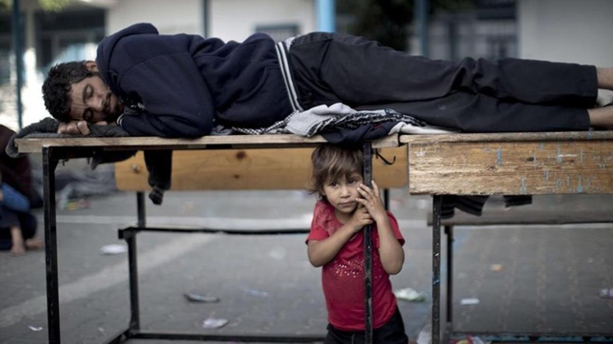 Un hombre palestino y un niño descansan en un refugio de la ONU tras huir del campo de refugiados de Jabaliya, en Gaza, este martes.