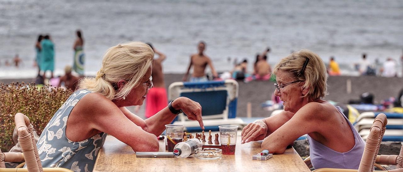 Dos turistas juegan al ajedrez junto a una playa de Tenerife.